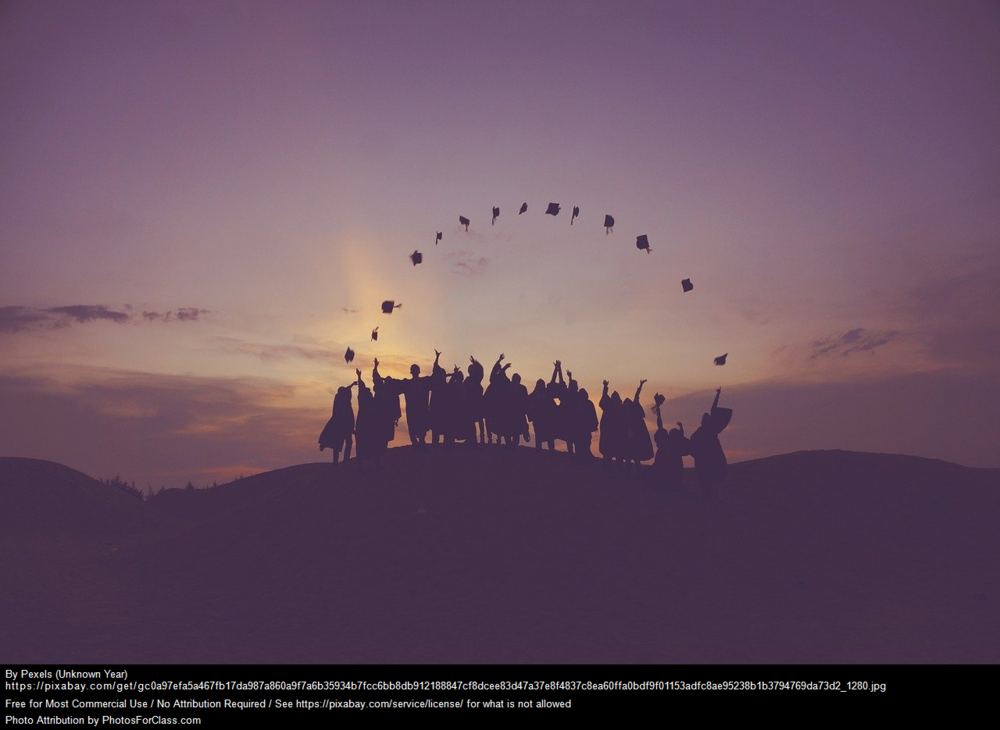 Graduates standing on a hill tossing their caps into the air making a circle